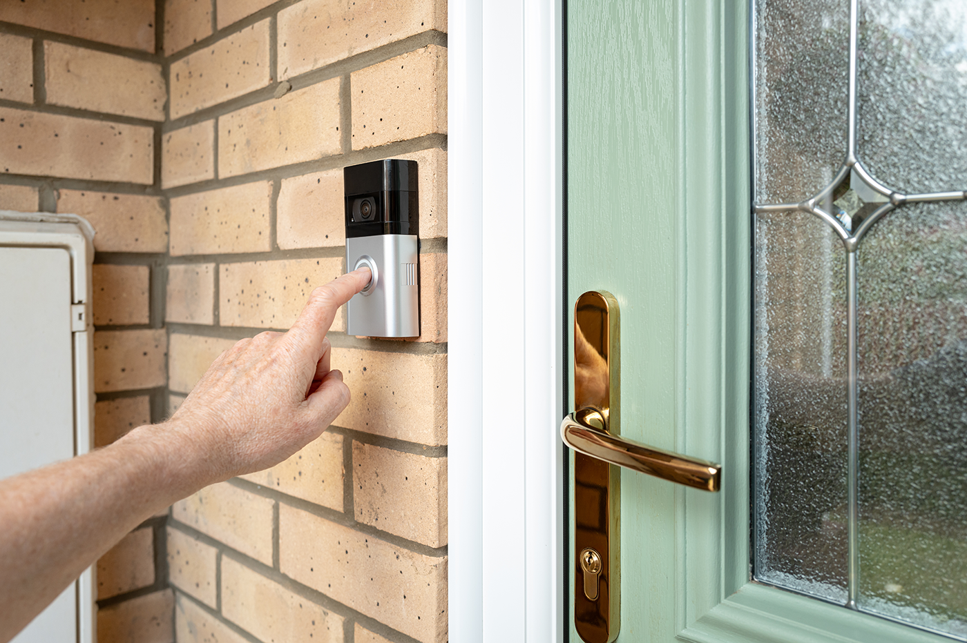 A person ringing a doorbell with a camera inside of it .